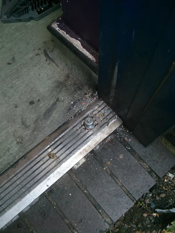 Bottom pivot and housing at the base of a commercial aluminium door during repair