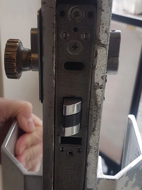 A mortice lock and deadbolt mechanism being fitted to a commercial door to keep it secure