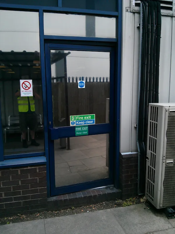 A blue commercial fire exit door with fire exit and keep clear signage