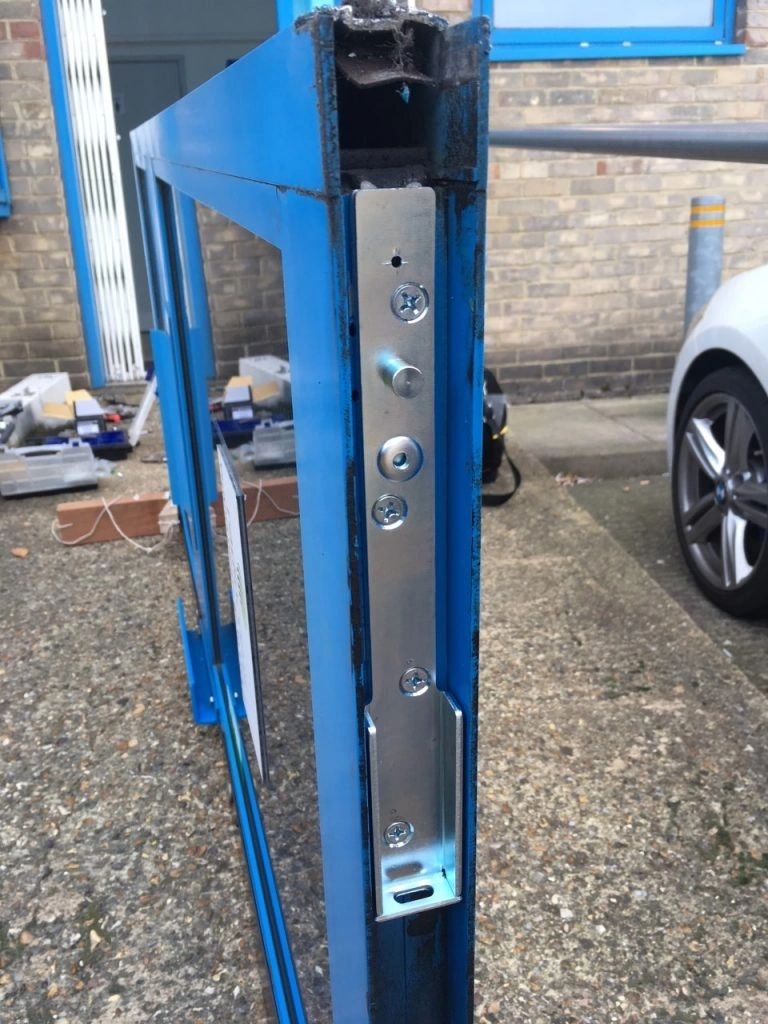 A new loading arm housing bracket fitted to the stile of a blue aluminium commercial door
