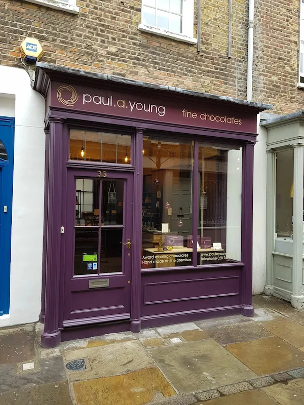 A purple-painted shop front with a glazed timber entrance door and display window