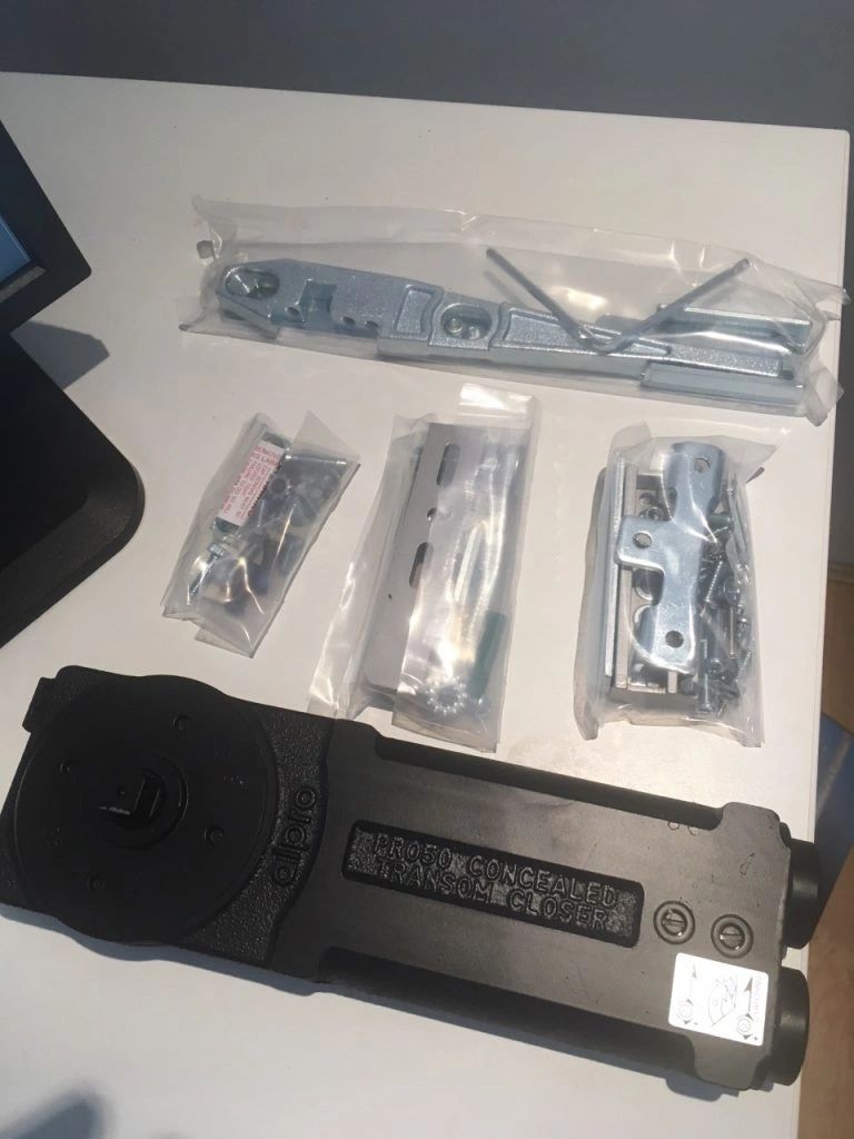 An Alpro concealed transom closer kit laid out ready to replace a worn commercial door closer