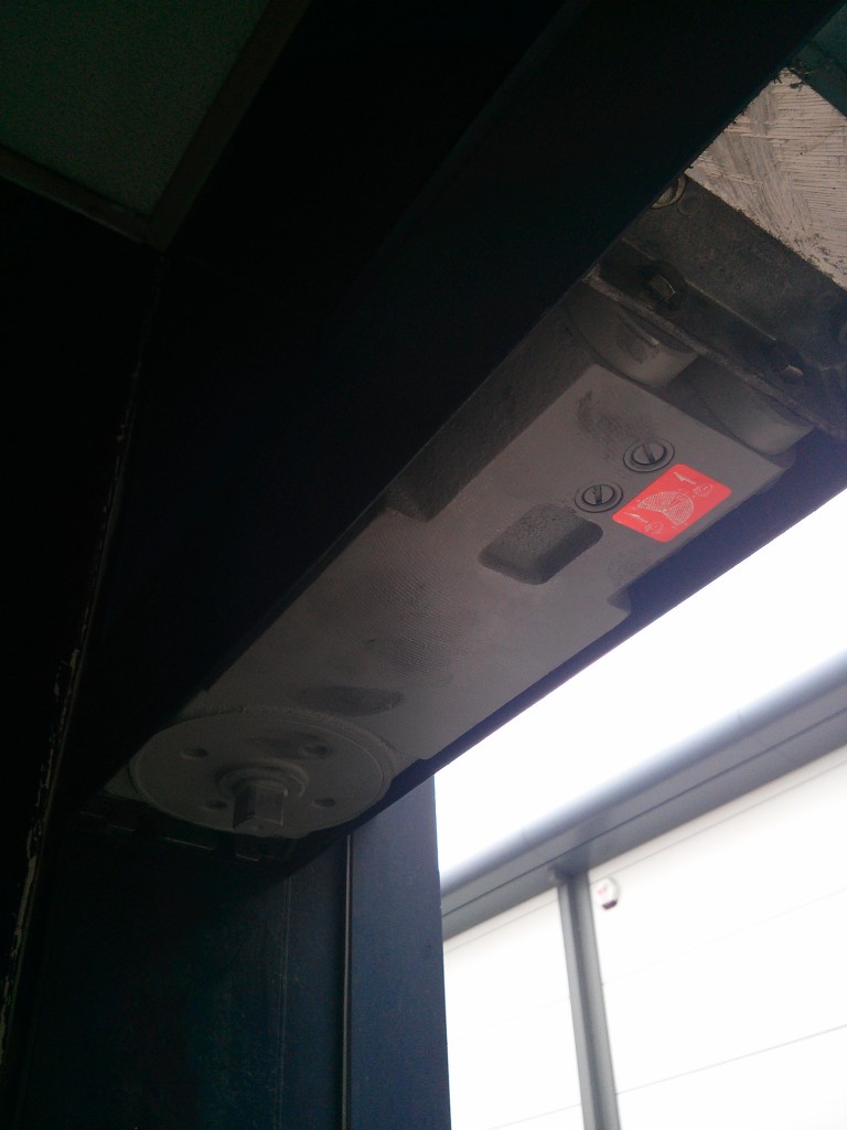 Concealed transom door closer removed from the head of a commercial aluminium door